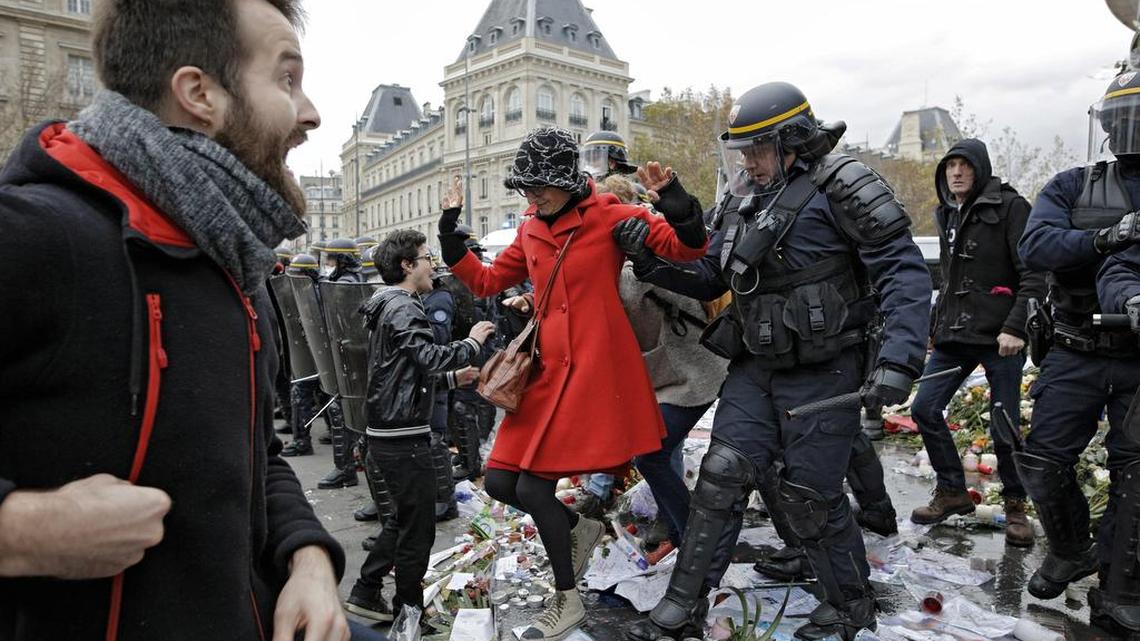 Policemen detain demonstrators on the candles and flowers set in memory of the victims of the Paris attacks during a protest ahead of the 2015 Paris Climate Conference at the place de la Republique on Sunday, Nov. 29, 2015. More than 140 world leaders are gathering for high-stakes climate talks that start Monday, and activists are holding marches and protests around the world to urge them to reach a strong agreement to slow global warming.