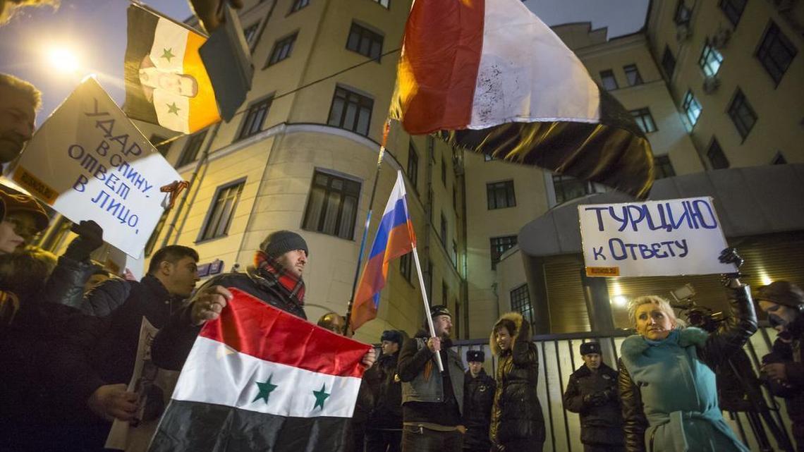 Protesters hold Russian and Syrian national flags and posters reading 'Turkey to account!' , right, and 'Stab in the back - a response in the face!' , left, during a picket at the Turkish Embassy in Moscow, Russia, Tuesday, Nov. 24, 2015. Russian President Vladimir Putin on Tuesday has called Turkey’s decision to down a Russian jet near the Syria border a “stab in the back.”