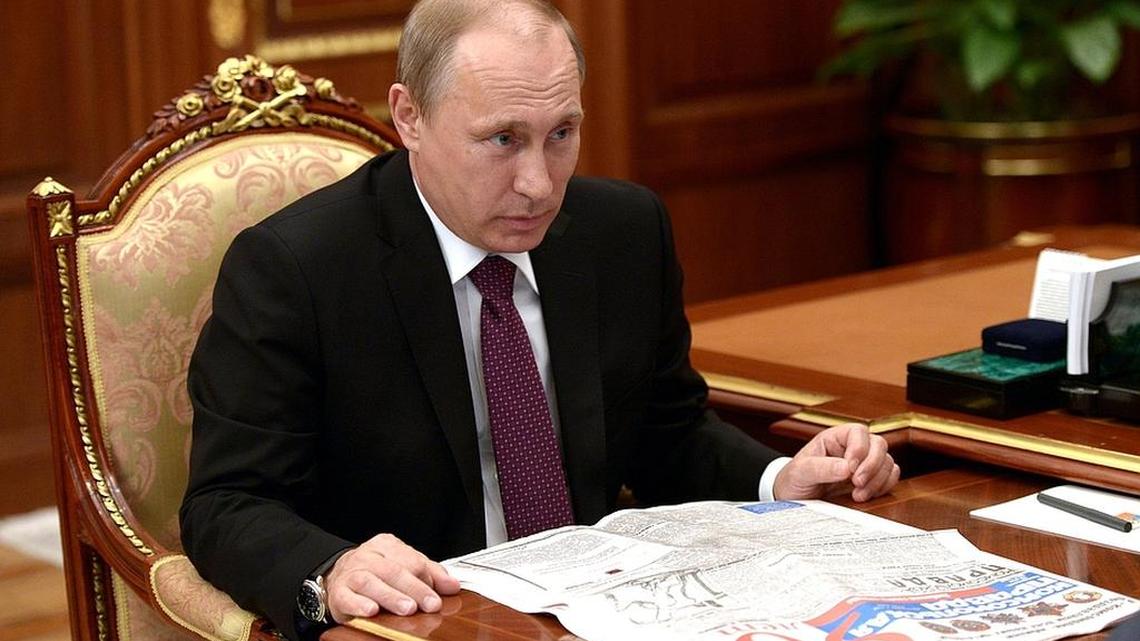 Russian President Vladimir Putin reads a copy of Komsomolskaya Pravda, a popular newspaper that published an article Tuesday that claims women who endure domestic violence are more likely to give birth to sons.