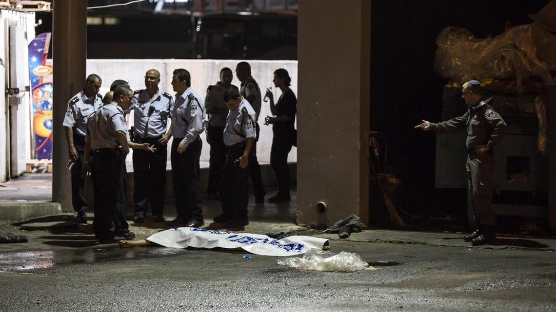 
Israeli police stand by the shrouded body of Palestinian attacker in Beersheba, Israel, Sunday, Oct. 18, 2015. 

