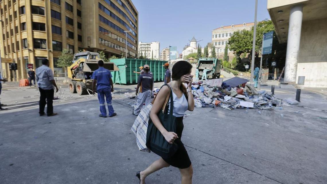 
A woman covers her nose as she passes waste management workers collecting garbage near the government building in downtown Beiruit on Monday.
