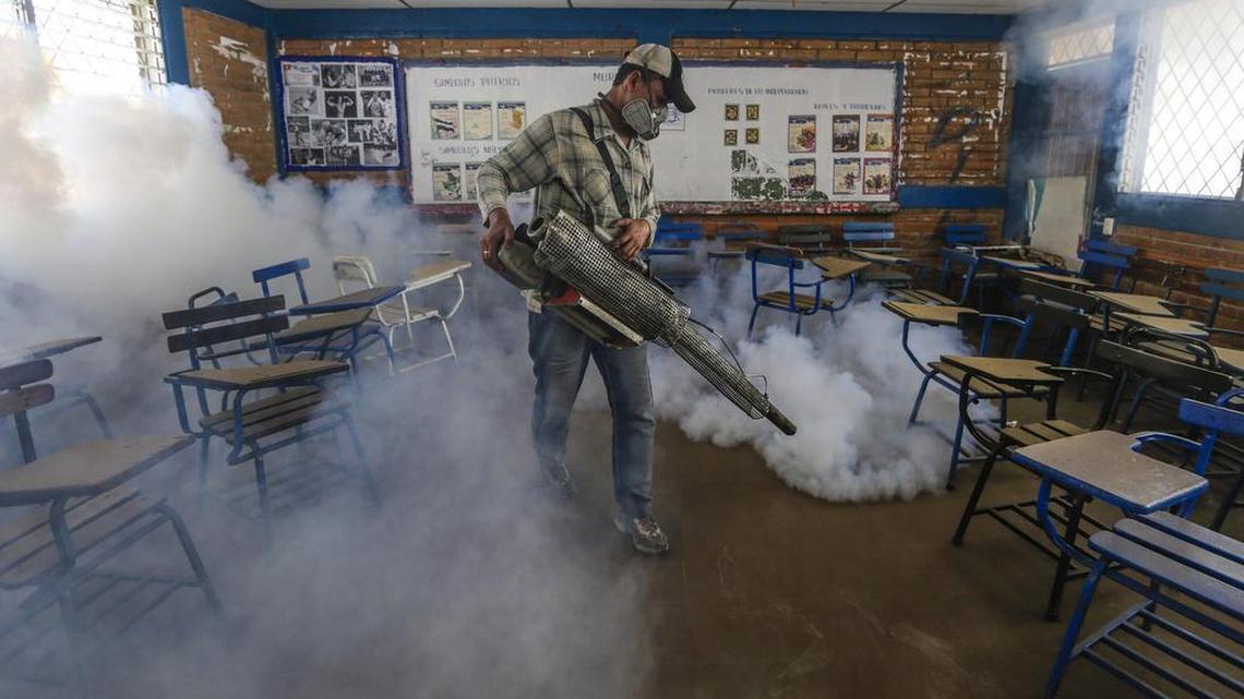In this Jan. 28, 2016 photo, a Health Ministry worker fumigates insecticide inside a classroom to combat Aedes aegypti mosquitoes that transmit the Zika virus in Managua, Nicaragua. Worries about the rapid spread of Zika through the hemisphere has prompted officials several Latin American countries to suggest women stop getting pregnant until the crisis has passed.
