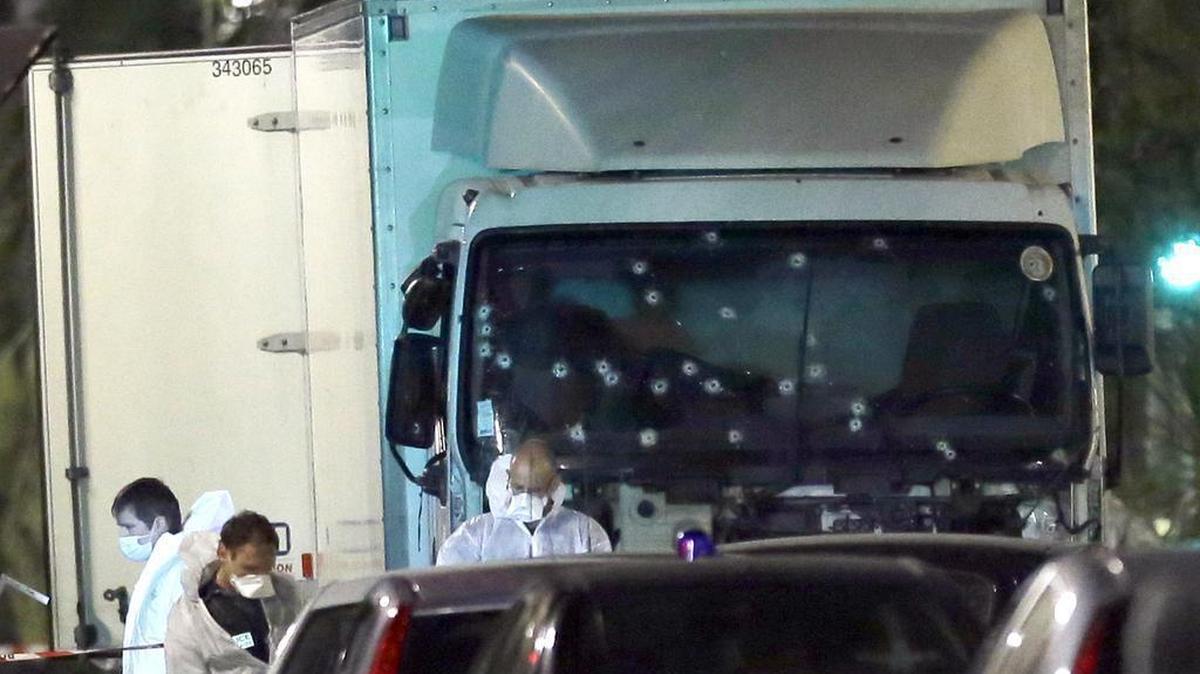 Forensic officers stands near a truck with its windscreen riddled with bullets, that plowed through a crowd of revelers who'd gathered to watch the fireworks in the French resort city of Nice, southern France, Friday. At least 80 people were killed before police killed the driver, authorities said.