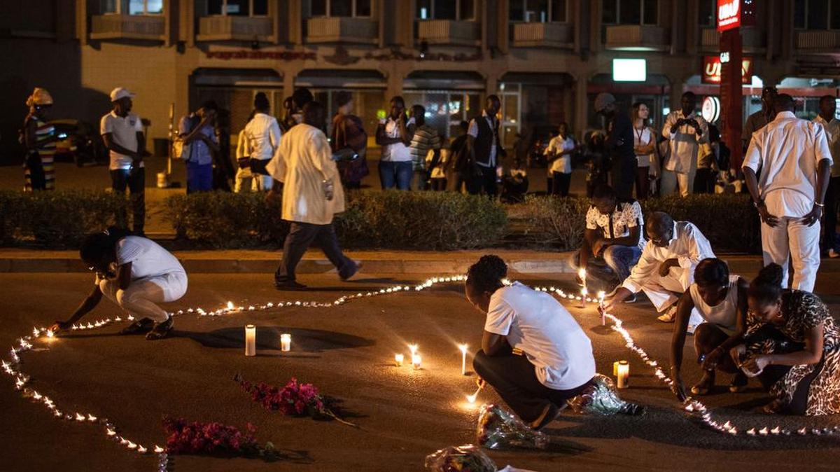 People light candles during the memorial ceremony on Jan. 23, 2016, for victims of the recent hotel and cafe attack where extremists killed foreigners and Burkina Faso nationals, in Ouagadougou, Burkina Faso. Burials have begun for the 10 Burkina Faso nationals.