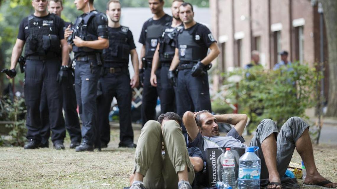 
Police keep watch on asylum seekers lying on the grass in front of the reception center for refugees in Berlin on Aug. 7, 2015. 
