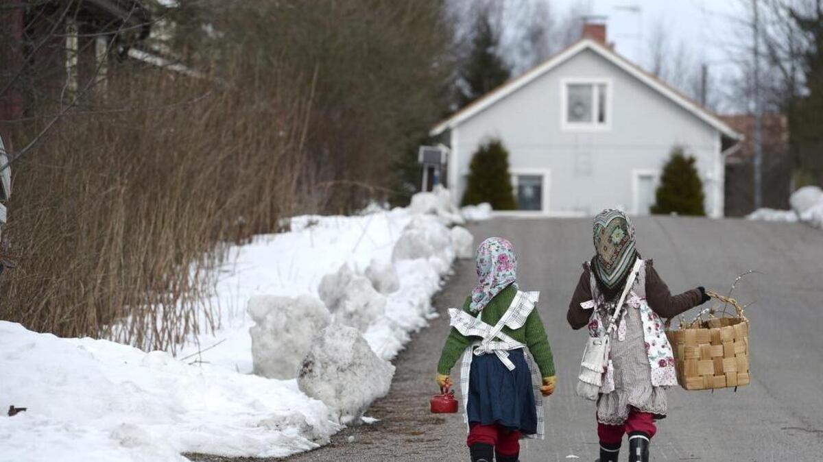 Two girls walks toward a house, in Jarvenpaa, Finland, on Sunday, March 20, 2016. Small colorful, witches appear on Finnish doorsteps before Easter, but instead of casting evil spells, they wish people well.
