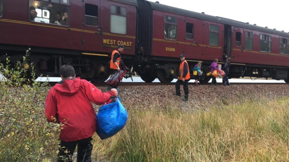 In this photo taken on Friday, Oct. 13, 2017, children run toward the Hogwarts Express train near Loch Eilt in the Scottish Highlands. The train from the “Harry Potter” movies made an unscheduled stop to pick up a family of six that was stranded when their canoe was washed away in a storm.