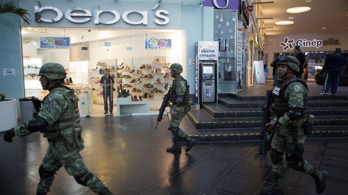 Soldiers walk inside Plaza Las Americas mall following reports of gunfire in Cancun, Mexico, Tuesday, Jan. 17, 2017. Gunmen attacked the state prosecutor's office in this Caribbean resort city Tuesday, ratcheting up tensions just a day after a deadly shooting at a music festival in a nearby town.