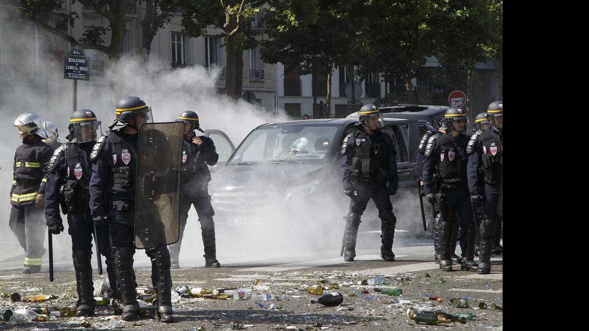 
Police officers stand next to a a burned-out car during a taxi driver strike in Paris on Thursday.
