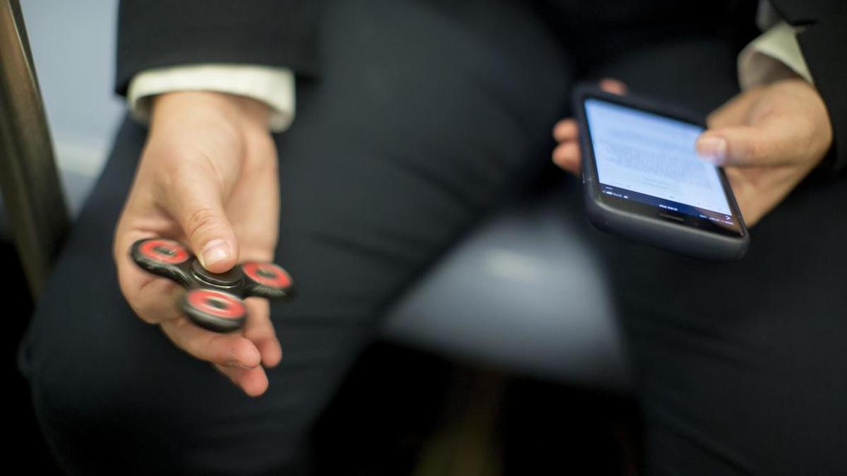 In this Wednesday, May 10, 2017, photo, attorney Kim Juszczak uses a fidget spinner while riding the subway in New York. Fidget spinners have been around for years, mostly used by kids with autism or attention disorders to help them concentrate. But they exploded in popularity this spring.