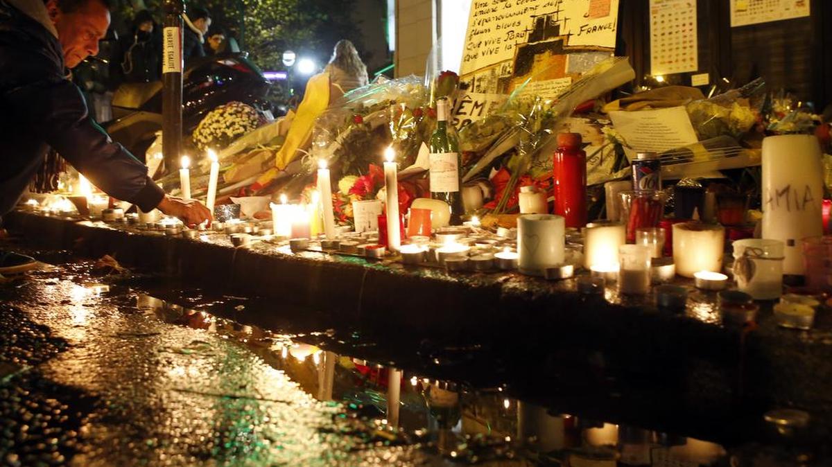 A man lights candles outside La Belle Equipe restaurant in Paris, Tuesday, Nov. 17, 2015, one of the spots of Friday's attacks.