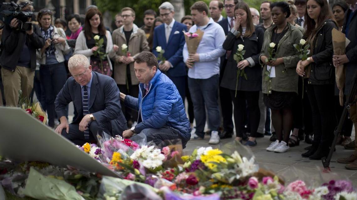 Staff from Britain's opposition Labour Party including at the front MP John Cryer, left, the Chair of the Parliamentary Labour Party and Iain McNicol, right, the party's General Secretary pay their respects after placing floral tributes for their colleague Jo Cox, the 41-year-old British Member of Parliament shot to death yesterday in northern England, on Parliament Square outside the House of Parliament in London, Friday, June 17, 2016.