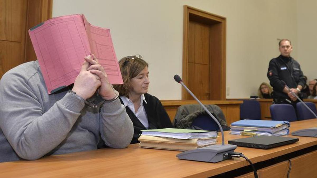 Former nurse Niels Hoegel, hiding his face, is already serving a life sentence for two murders and has been indicted in nearly 100 more killings.