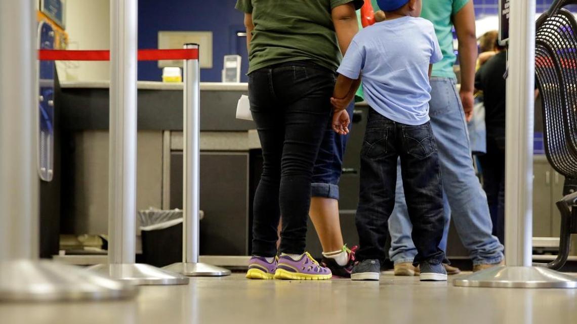 In this photo taken July 7, 2015, immigrants from El Salvador who entered the country illegally stand in line at a bus after they were released from a family detention center in San Antonio.