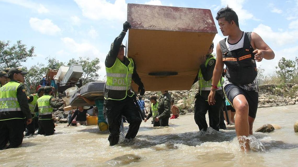 
Colombian police help fellow citizens carry their belongings across the Tachira River into Colombia’s community of La Parada, across the border with San Antonio del Tachira, Venezuela, Tuesday, Aug. 25, 2015. Venezuelan President Nicolas Maduro vowed to extend a crackdown on illegal migrants from neighboring Colombia he blames for rampant crime and widespread shortages, while authorities across the border struggled to attend to droves of returning deportees. 

