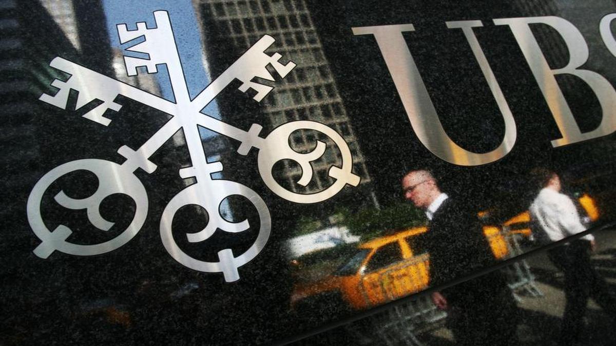 Pedestrians are reflected below a UBS office building logo in New York on May 6, 2008.