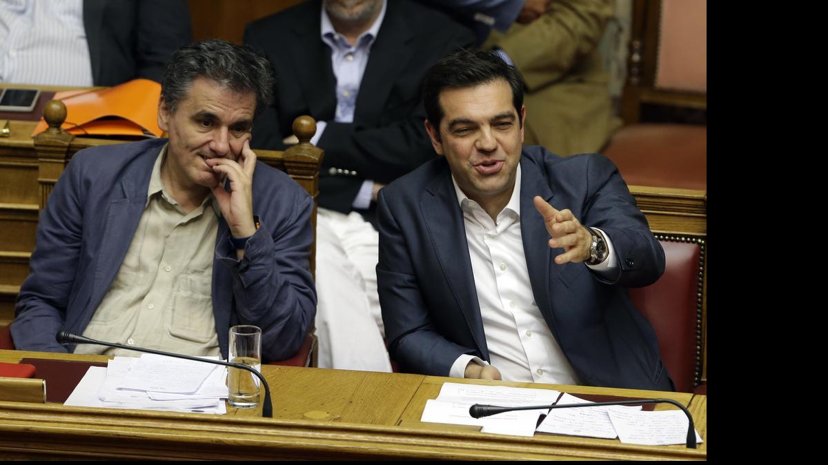 
Greek Prime Minister Alexis Tsipras, right, and Finance Minister Euclid Tsakalotos take part in a parliament meeting in Athens, Thursday, July 16, 2015. Tsipras was fighting to keep his government intact in the face of outrage over an austerity bill that parliament must pass if the country is to start negotiations on a new bailout and avoid financial collapse. 
