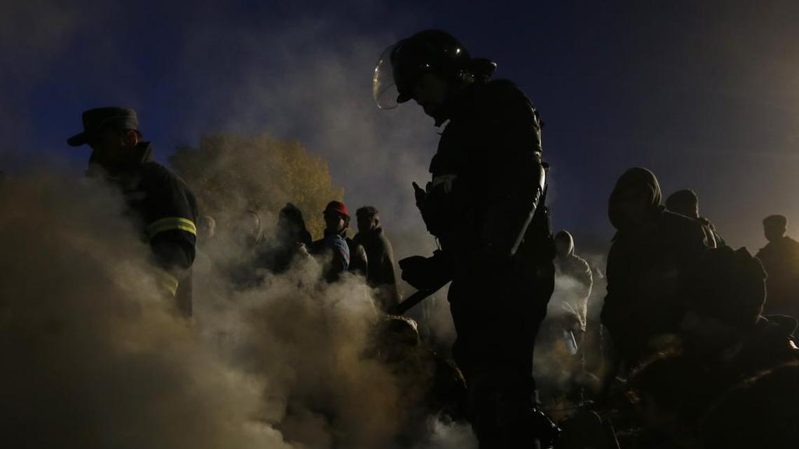 Slovenian policeman extinguish a fire where migrants were trying to warm up while waiting to enter a camp in Spielfeld, Austria, Sunday, Oct. 25, 2015. Thousands of people are trying to reach central and northern Europe via the Balkans but often have to wait for days in mud and rain at the Serbian, Croatian and Slovenian borders.