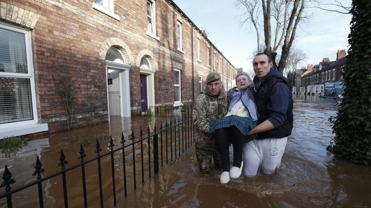 Margaret McCraken, 79, is helped from her home in Carlisle, northwest England, through the floods by members of the armed forces who have been called in to help evacuate people who wish to move Sunday. The Environment Agency declared 130 flood warnings, while residents in some areas were evacuated from their homes.