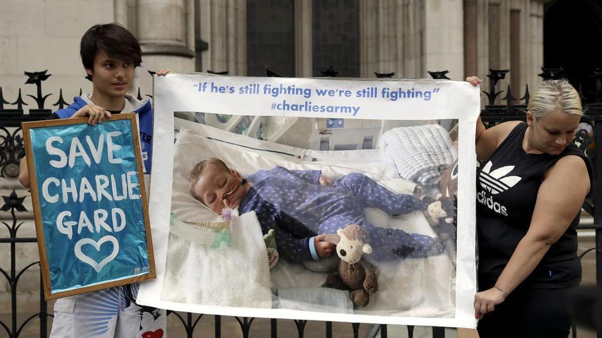 Supporters of critically ill baby Charlie Gard hold up a photograph of him after his court case finished for the day at the High Court in London on July 14. The parents of the 11-month old said the baby died on Friday.