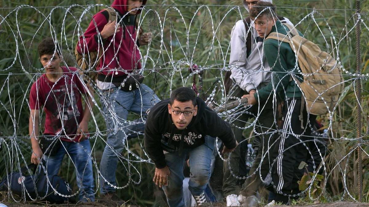 
A Syrian refugee runs after entering Hungary from Serbia through a barbed wire fence, on the border near Roszke, Friday, Aug. 28, 2015. Hungary deployed police reinforcements to rein in an unrelenting flow of migrants across its porous border Thursday, but refugee activists said the effort appeared futile in a nation whose migrant camps are overloaded and barely delay their journeys west into the heart of the European Union. 
