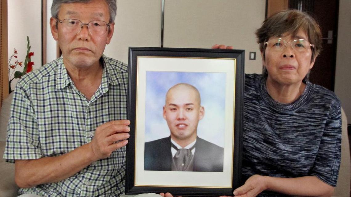 Kiyoshi, left, and Mitsuko Serizawa sit in their living room with a portrait of their son, Kiyotaka, who killed himself a year ago after working 90-hour weeks as a supervisor at a building maintenance company.