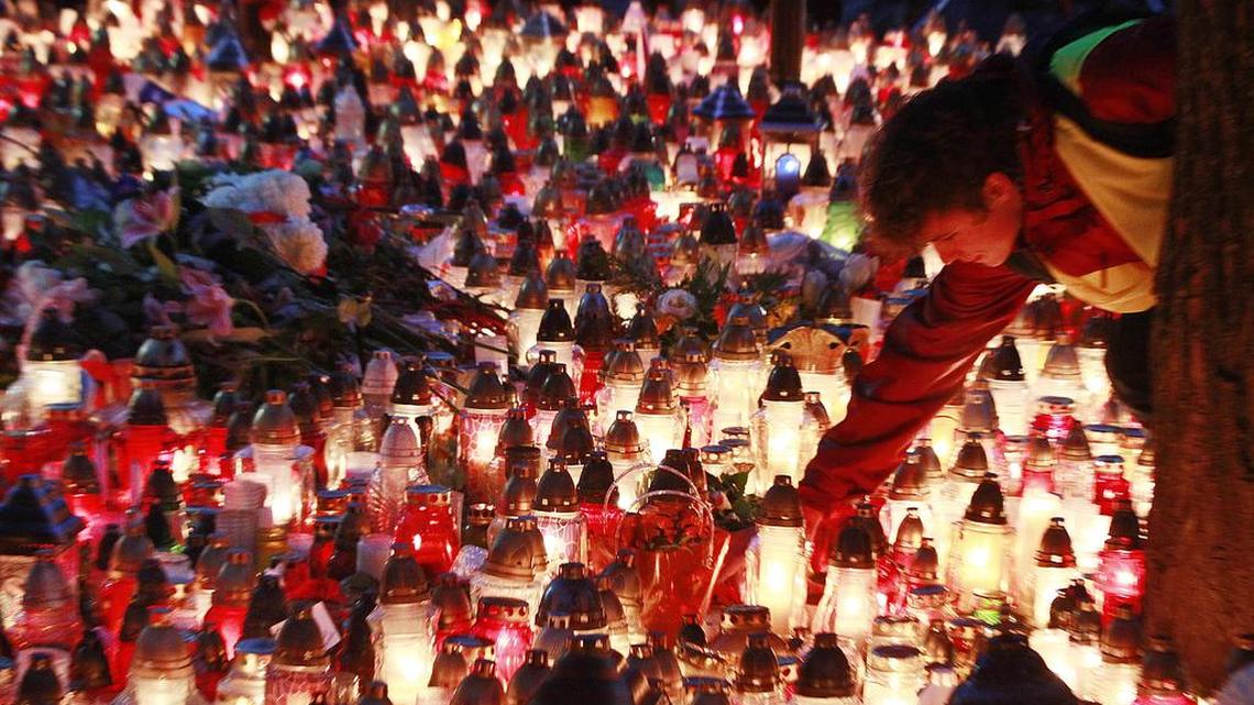 A man places a candle outside the French embassy in Warsaw, Poland, on Sunday, Nov. 15, 2015, two days after attacks in the French capital on a stadium, a concert hall and cafes that left more than 120 people dead and over 350 wounded.