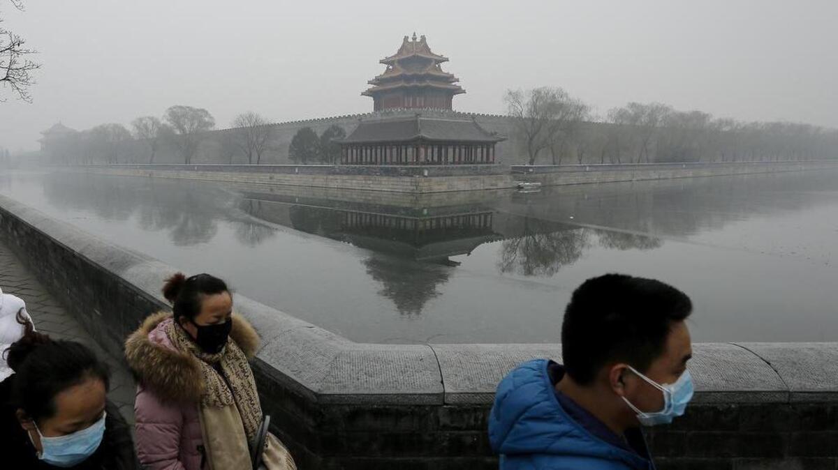 People wearing masks walk past the Turret of the Forbidden City on a heavily polluted day in Beijing Dec. 8, 2015.