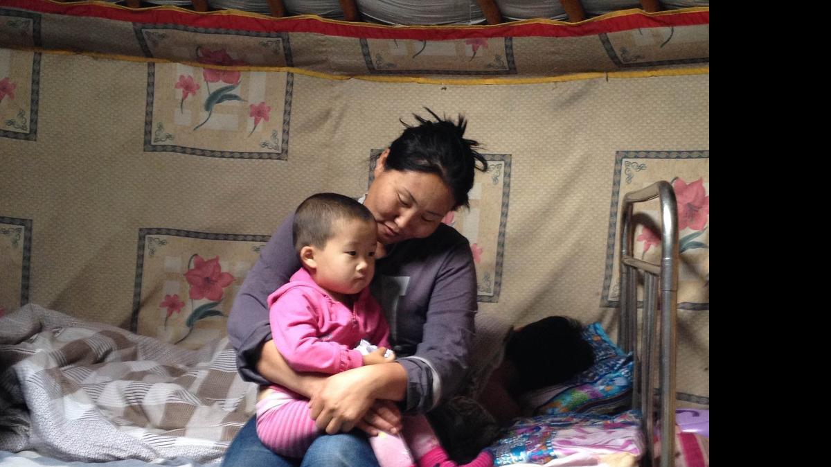
Unurbileg, a Mongolian herder, holds one of her daughters, Bujinlkham, 2, inside the family's yurt in grasslands near the Tuul River in central Mongolia on July 13, 2015. Her husband, Duuree, sleeps in the background after a long day of watching and herding the family's sheep, horses and other animals. Unurbileg – who like many Mongolians only uses one name – says her family is doing well, evidenced by the satellite dish and new Toyota SUV they have outside their yurt. But she worries about the future. A single cold winter could wipe out the family’s wealth, their livestock.
