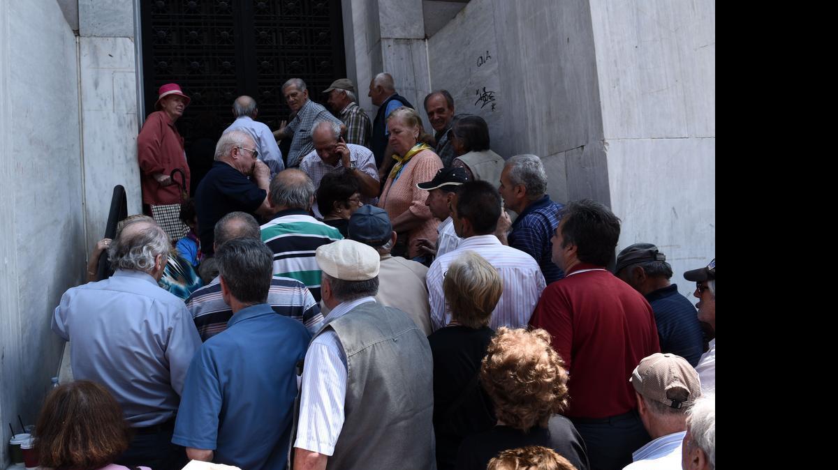
Elderly people, who usually get their pensions at the end of the month, wait outside a closed bank in the northern Greek port city of Thessaloniki, Monday, June 29, 2015. Greece's five-year financial crisis took its most dramatic turn yet, with the cabinet deciding that Greek banks would remain shut for six business days and restrictions would be imposed on cash machine withdrawals. 
