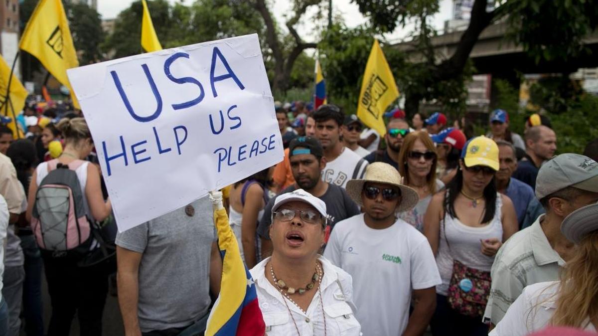A woman holds up a sign asking for help from the United States during a protest against Venezuela's President Nicolas Maduro in Caracas, Venezuela, Wednesday, Oct. 26, 2016.