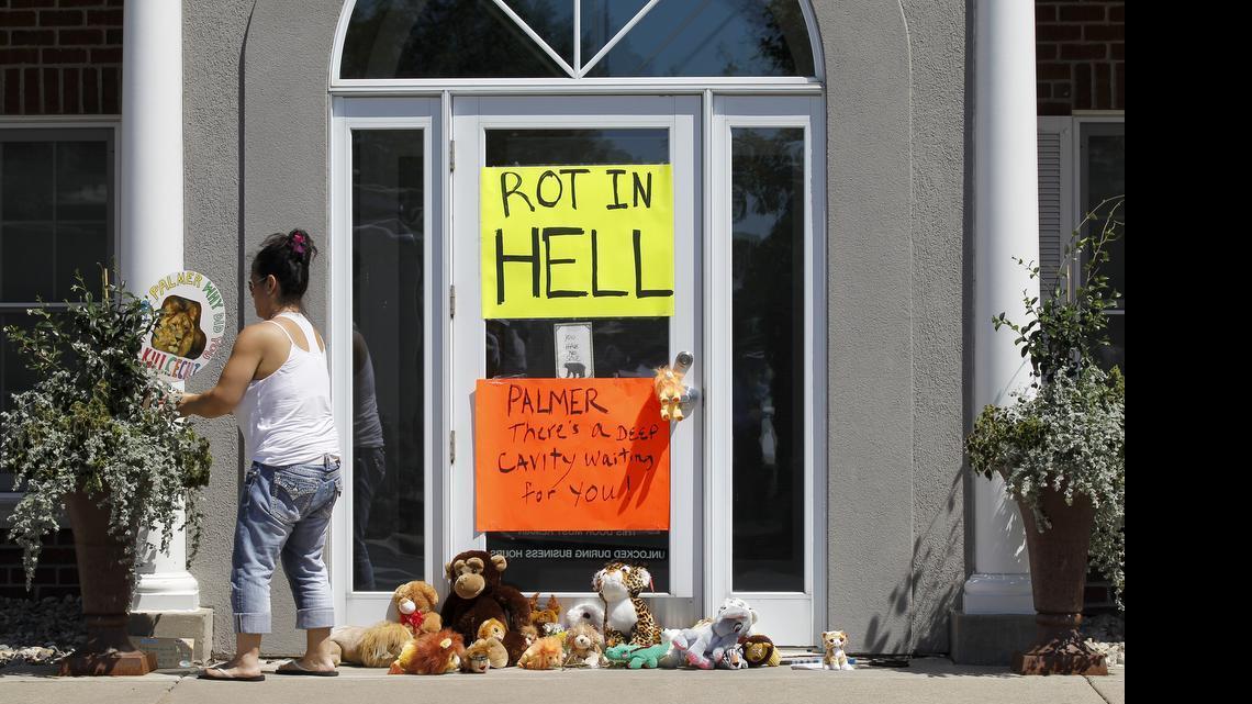 
A woman moves a sign outside Dr. Walter James Palmer's dental office in Bloomington, Minn., Wednesday, July 29, 2015. Palmer reportedly paid $50,000 to track and kill Cecil, a black-maned lion, just outside Hwange National Park in Zimbabwe. 
