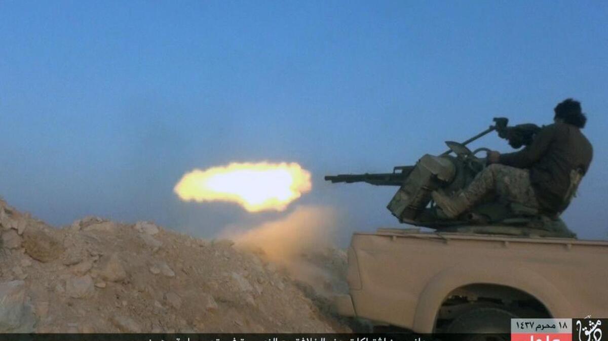 This image posted Sunday, Nov. 1, 2015, by a website used by Islamic State militants, shows an Islamic State fighter firing his weapon during a battle against Syrian government troops in the village of Mahin, central Homs province, Syria. The Islamic State said a suicide bomber attacked a Kurdish-led column of armored vehicles Sunday, including tanks and armored personnel carriers, killed dozens of Arabs and members of the Kurdish People’s Protection Units, or YPG.