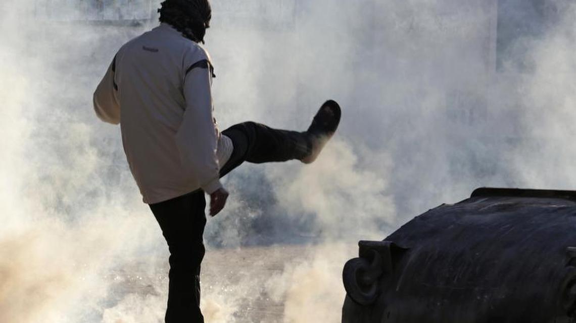 A Bahraini anti-government protester kicks away a tear gas canister fired by riot police in Sitra on on Sunday, Feb. 14, 2016. Hundreds of Bahraini youths shouting anti-government slogans have taken to the streets in Bahrain despite a heavy police presence to mark the fifth anniversary of an uprising calling for political change in the tiny island kingdom.