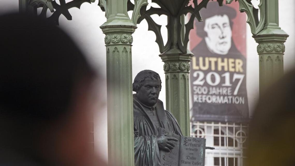 Visitors walk in front of the Martin Luther monument prior the celebrations on the occasion the 500th Anniversary of the Reformation in Wittenberg, Germany, Tuesday, Oct. 31, 2017.