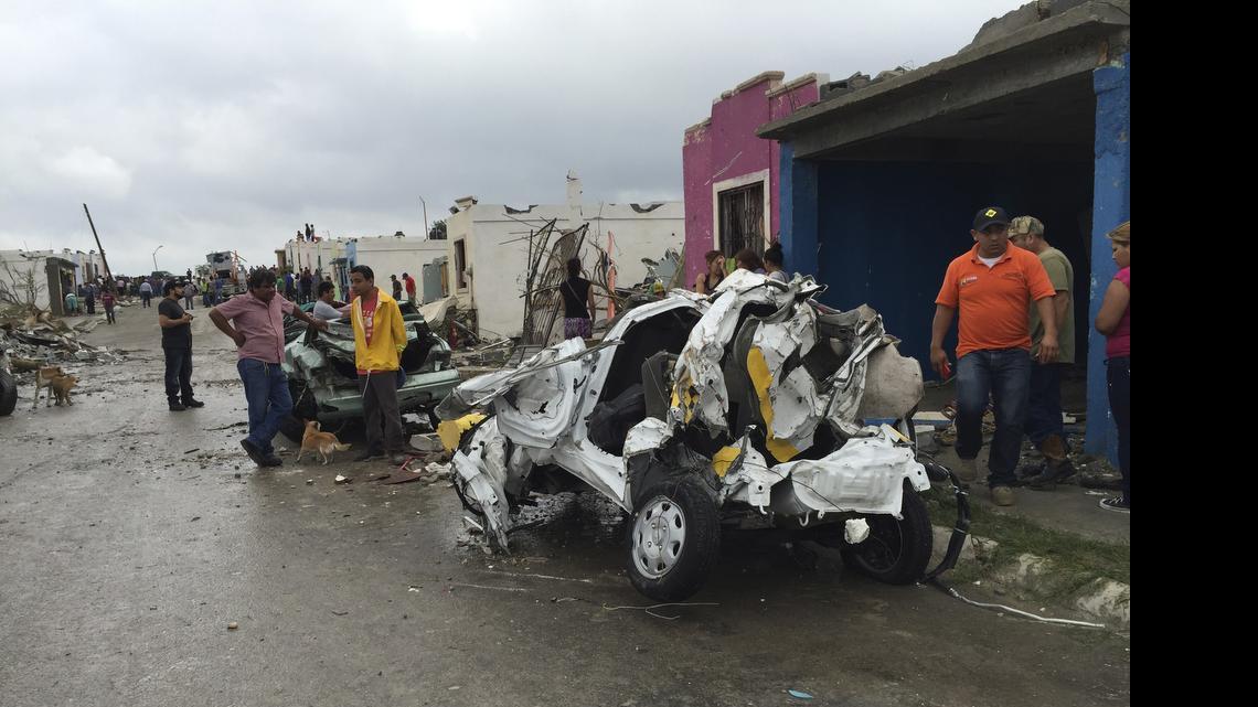 
People stand near damaged homes and vehicles after a powerful tornado swept past in Ciudad Acuna, northern Mexico, Monday, May 25, 2015. A tornado raged through the city on the U.S.-Mexico border Monday, destroying homes and flinging cars like matchsticks. At least 13 people were killed, authorities said. The twister hit a seven-block area, which Victor Zamora, interior secretary of the northern state of Coahuila, described as "devastated." 
