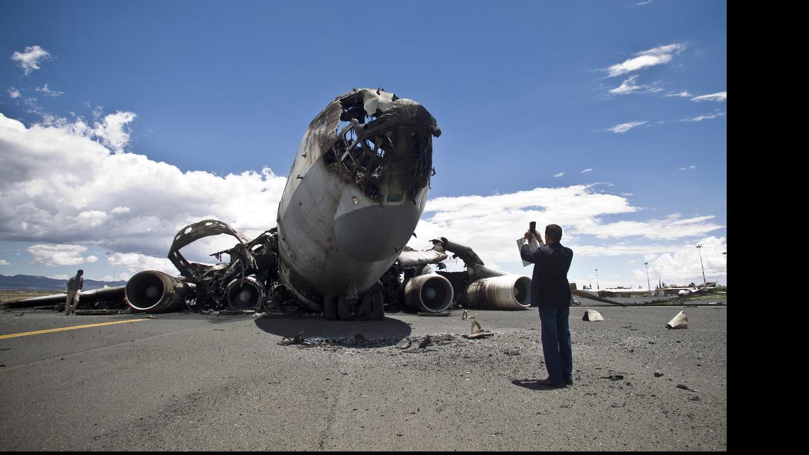 
An airport official uses his mobile to take pictures of the wreckage of a military transport aircraft destroyed by Saudi-led airstrikes, at the Sanaa International airport, in Yemen, Tuesday, May 5, 2015. A Saudi-led coalition continues to bomb Shiite rebels also known as Houthis and allied forces across the country. 
