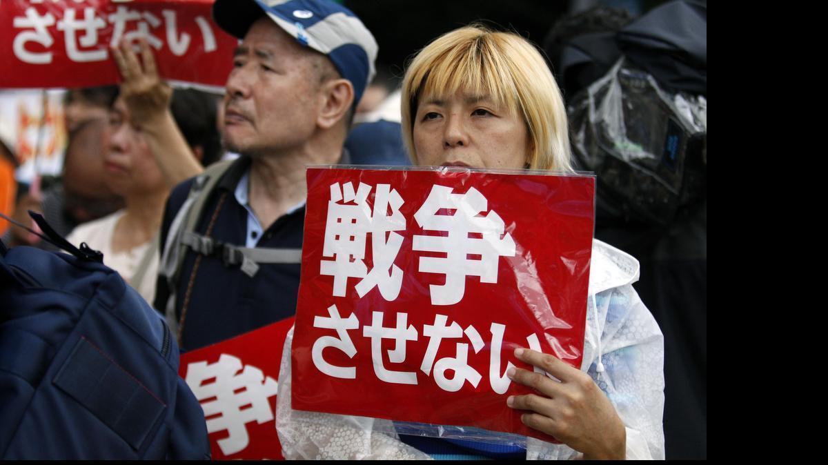 
Protesters holding anti-war placards stage a rally in front of the Parliament building in Tokyo after Japan's lower house of parliament approved legislation that would expand the role of the nation's military Thursday. The placards read: "No war." 
