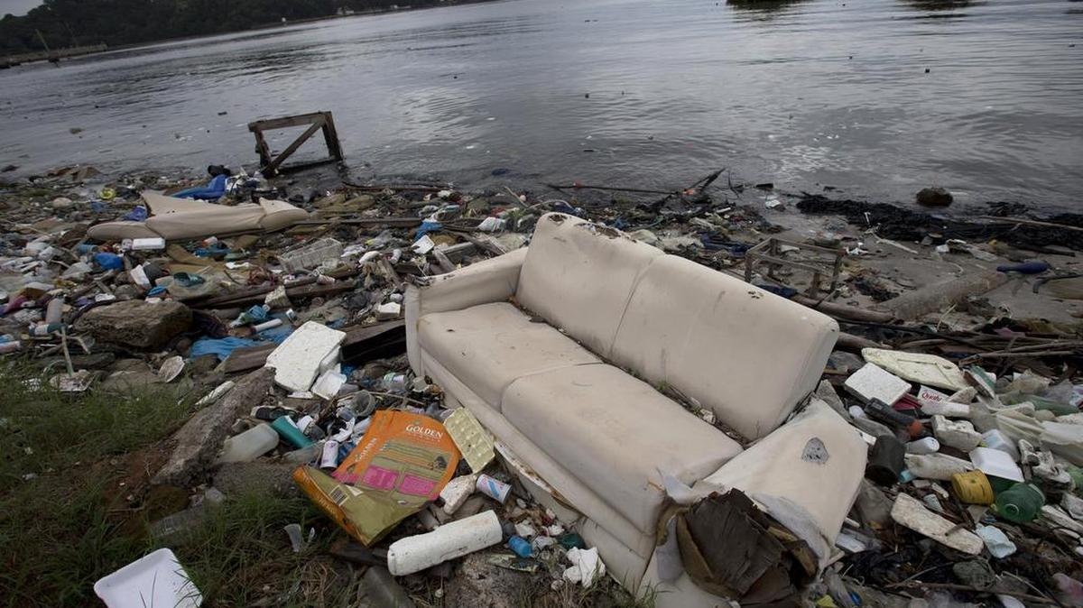 In this June 1, 2015 file photo, a discarded sofa litters the shore of Guanabara Bay in Rio de Janeiro, Brazil. With thousands of liters of raw human sewage pouring into the ocean every second from Rio, August's Olympic Games have thrust into the global spotlight Rio's spectacular failure to clean up its waterways and world famous beaches.