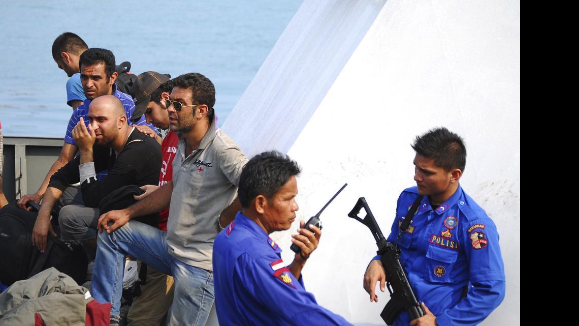 
In this Oct. 12, 2012, file photo, Indonesian police officers guard asylum seekers on a patrol boat upon arrival at a port in Merak, Banten province, Indonesia. More than 60 asylum seekers from Pakistan, Iraq, and Afghanistan were on a boat en-route to Australia when they were caught and detained by Indonesian authorities. Two recent shipwrecks in the Mediterranean Sea believed to have taken the lives of as many as 1,300 asylum seekers and migrants has highlighted the escalating flow of people fleeing persecution, war and economic difficulties in their homelands. 
