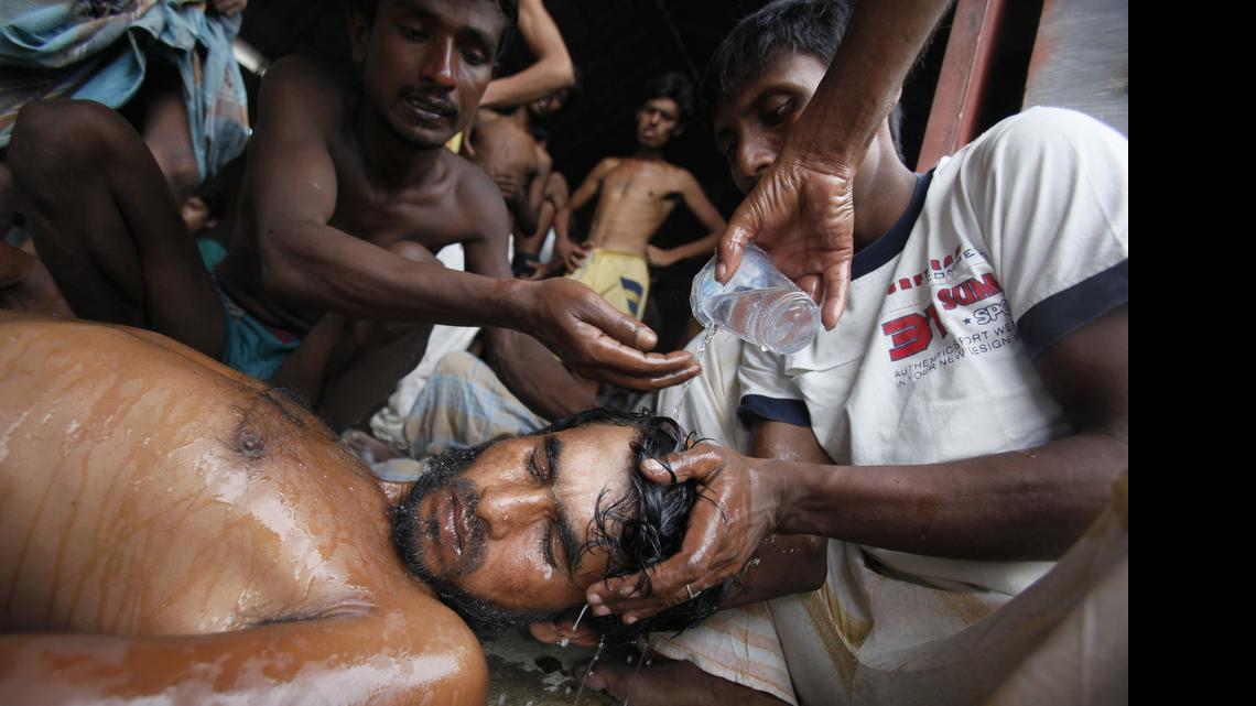 
Newly arrived Bangladeshi migrants pour water on the head of a man who had fainted at Kuala Langsa Port in Langsa, Aceh province, Indonesia, Friday, May 15, 2015. Hundreds of Bangladeshi and ethnic Rohingya migrants have landed on the shores of Indonesia and Thailand after being adrift at sea for weeks, authorities said Friday. 
