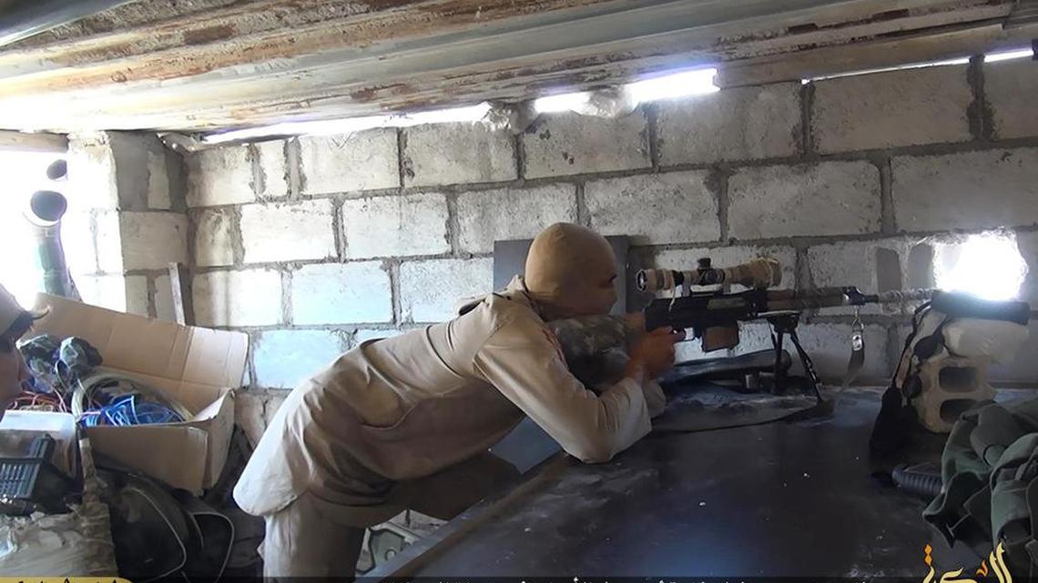 In July 13, 2015, an Islamic State militant sniper takes position during a battle against Syrian government forces, in Deir el-Zour province, Syria. In the besieged eastern city of Deir el-Zour, supplies are running so short that people are selling their gold and other property for food or an exit permit allowing them to escape both the government and Islamic State militants who rule the region of Syria.