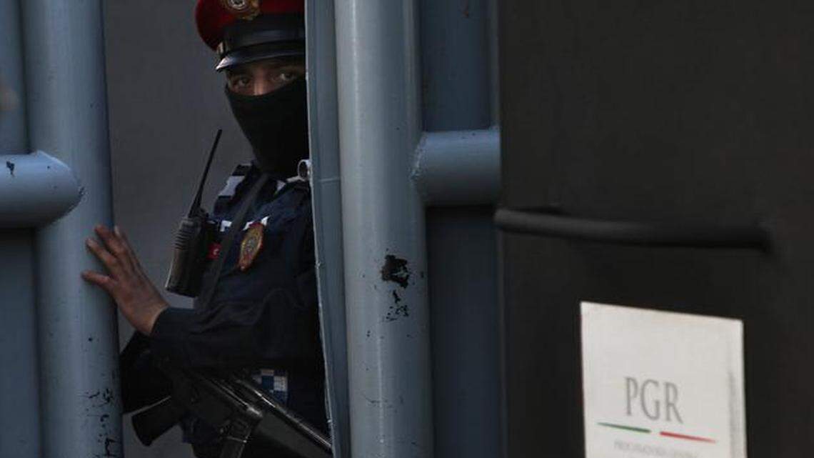 
A masked federal police officer stands guard as part of increased security at the organized-crime division of Mexico’s Attorney General Office where high profile detainees are sometimes held and shown to the press in Mexico City, Feb. 27, 2015. 
