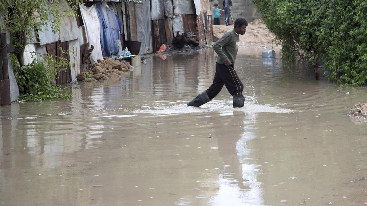 A Palestinian man walks across a flooded street on his way home following a rainstorm in Gaza City, Tuesday, Nov. 17, 2015.