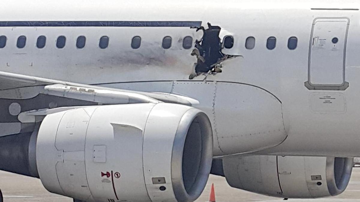 A hole is photographed in a plane operated by Daallo Airlines as it sits on the runway of the airport in Mogadishu, Somalia. A gaping hole in the commercial airliner forced it to make an emergency landing at Mogadishu's international airport late Tuesday, officials and witnesses said.