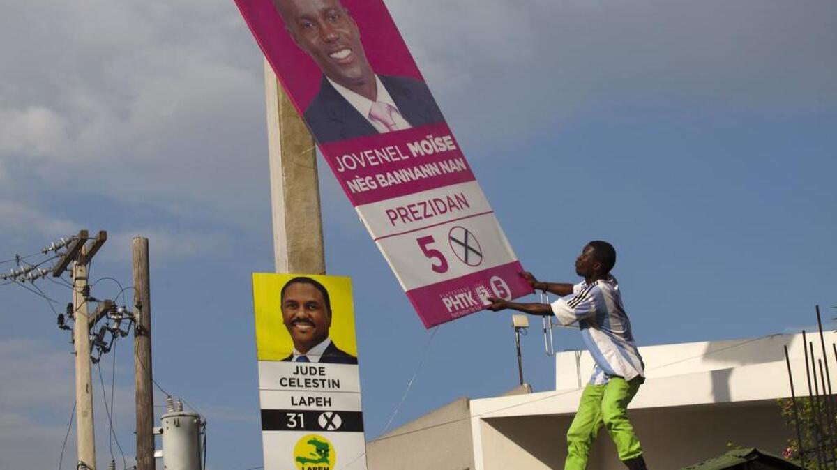 Supporters of presidential candidate Maryse Narcisse, of the Lavalas party, remove an election campaign sign of presidential candidate Jovenel Moise, in front of a sign of his rival, Jude Celestin, during a protest against election results in Port-au-Prince, Haiti. Celestin and the other presidential candidates that dub themselves the “Group of Eight” have been demanding an independent recount due to what they assert was “massive fraud” in favor of Moise, the government-backed contender in October elections.