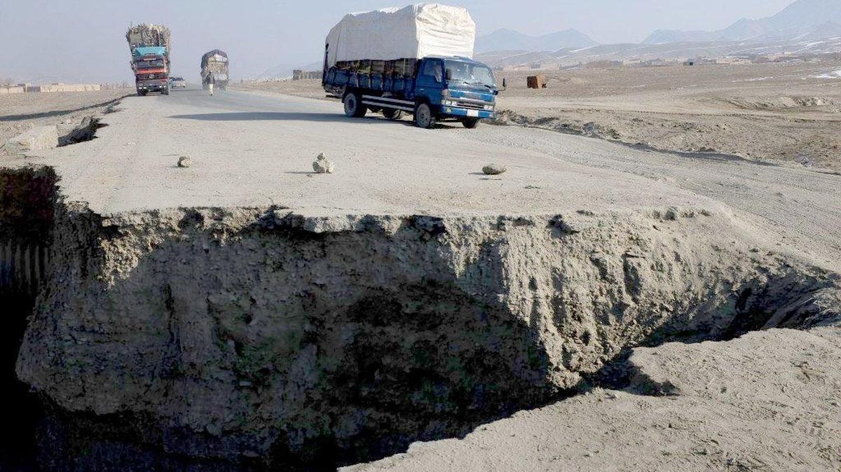 In this 2013 photo, a vehicle drives along a stretch of Highway One damaged by a roadside bomb in Sayedabad, Afghanistan.