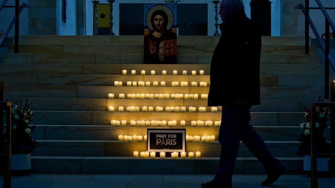 A man passes candles placed for t victims of the Paris attacks Friday night, in front of the Hildesheim cathedral in Hildesheim northern Germany, on Saturday, Nov. 14, 2015. French President Francois Hollande said more than 120 people died Friday night in shootings at Paris cafes, suicide bombings near France's national stadium and a hostage-taking slaughter inside a concert hall.