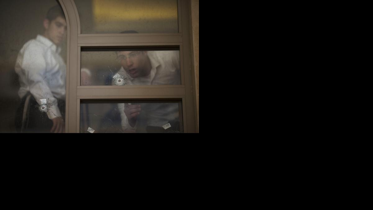 
Two youths look at bullet holes and forensic evidence inside a synagogue after an attack in Jerusalem, Tuesday, Nov. 18, 2014. Two Palestinians stormed a Jerusalem synagogue on Tuesday, attacking worshippers praying inside with knives, axes and guns, and killing four people before they were killed in a shootout with police, officials said. 
