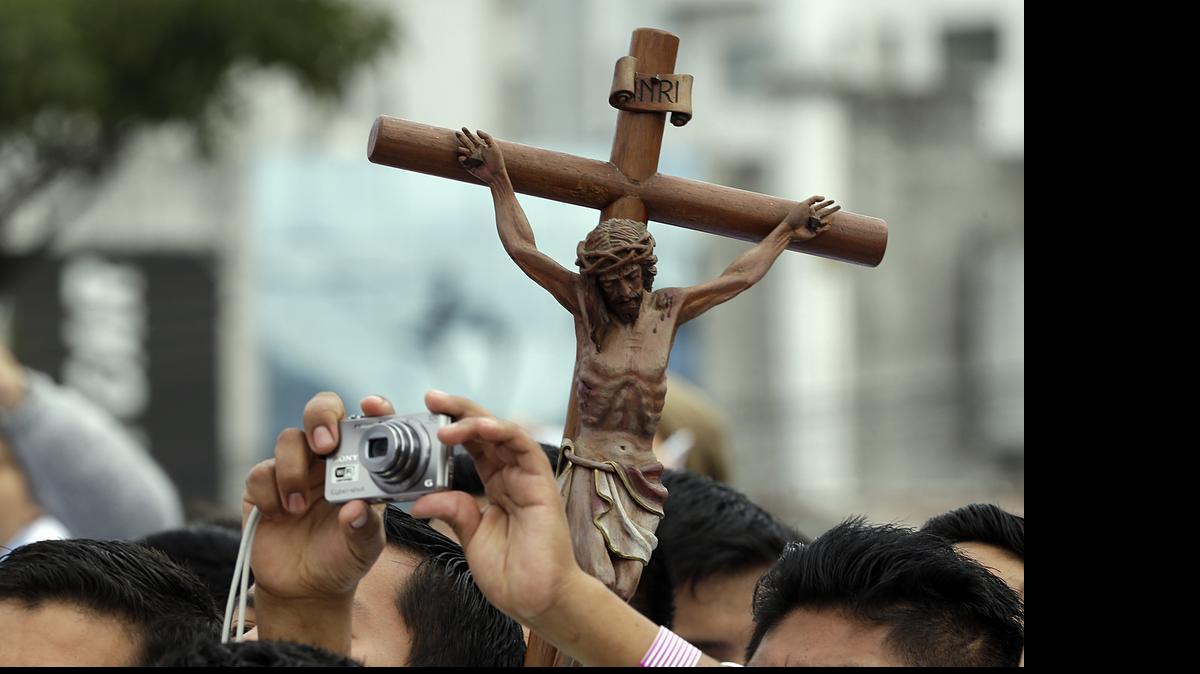 
Backdropped by a crucifix, a seminarian reaches up to make a photo as he waits with other seminarians for the arrival of Pope Francis, at Christ the Redeemer square in Santa Cruz, Bolivia, Thursday, July 9, 2015. Hundreds of thousands packed the square and the streets beyond. Overnight, several thousand slept in square to get a spot close to the front. Francis arrived in the Andean nation late Wednesday after three days in Ecuador.
